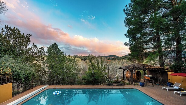 A swimming pool with lounge chairs and a rustic building in the background.
