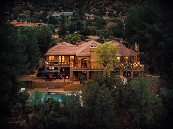 A large house with a pool, surrounded by trees and hills.