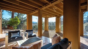 An outdoor patio with wooden furniture and a view of the surrounding landscape.