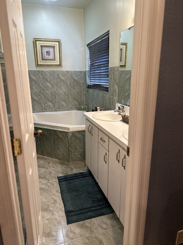 A bathroom with a bathtub, a sink, and a mirror.
