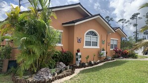 A house with a well-maintained lawn, a stone pathway, and various plants and flowers. - Quiet Haven  (Freeport)