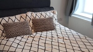 A bed with a checkered bedspread and two patterned pillows. - Bike Park Cottage Sleeps 5 With Pet (Merthyr Tydfil)