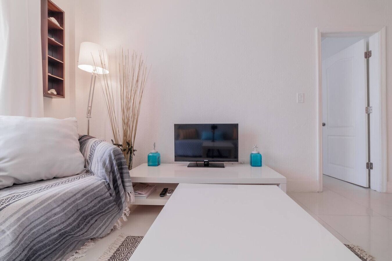 A modern bedroom with a bed, a TV, a bedside table, and a door.