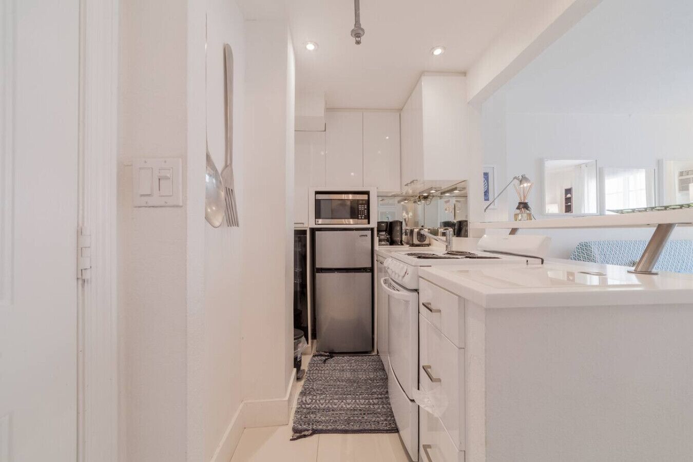 A modern kitchen with white cabinets, stainless steel appliances, and a large window providing natural light.