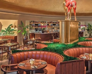 Een restaurant met lederen zithoeken, een bar en een centraal decoratief beeldhouwwerk.