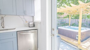 Una cocina con lavavajillas, ventana y vistas a un patio trasero con hidromasaje.