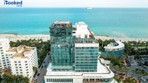 A modern hotel with a glass facade overlooking a beach. - Newly remodeled apartment only 1 min to the beach! (Miami Beach)