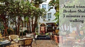An outdoor patio area with various seating options, a small fountain, and a restaurant in the background. - Newly remodeled apartment only 1 min to the beach! (Miami Beach)