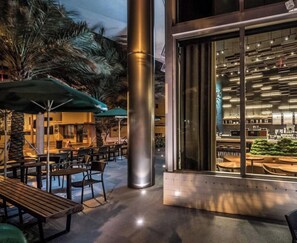 An outdoor seating area with tables and chairs, a palm tree, and a Starbucks sign indicating it's 2 minutes away.