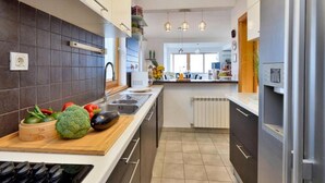 A modern kitchen with dark tiles, a wooden countertop, and a built-in stove.
