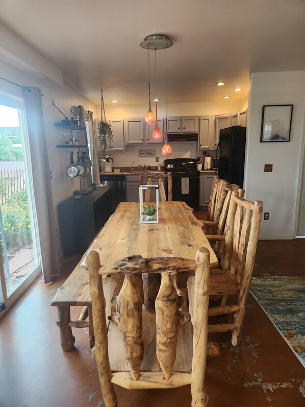 Una cocina amplia con armarios blancos, un refrigerador negro y una mesa de comedor de madera con sillas variadas.