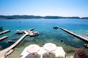 A marina with boats docked, clear water, and a pier with umbrellas and lounge chairs. - Villa Gulli - Apartment Gold with Private Beach (Supetarska Draga)