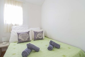 Cozy retreat with a single bed, bedside table, and sheer curtains.