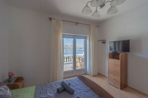 Relax on the balcony through the large sliding glass door, featuring a comfortable bed and a flat-screen TV.