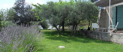 A garden with a stone wall, a pergola, and outdoor furniture.