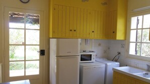 Une cuisine compacte équipée d’un réfrigérateur, d’un four à micro-ondes et d’un lave-linge.