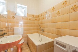 Bathroom features a white toilet, sink, and bathtub, set against a backdrop of floral-patterned tiles.