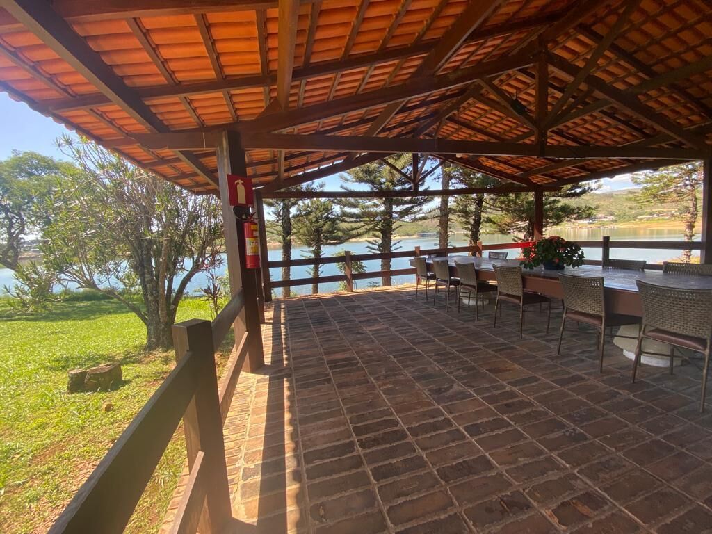 An outdoor patio with a tiled floor, wooden tables and chairs, and a view of a lake.