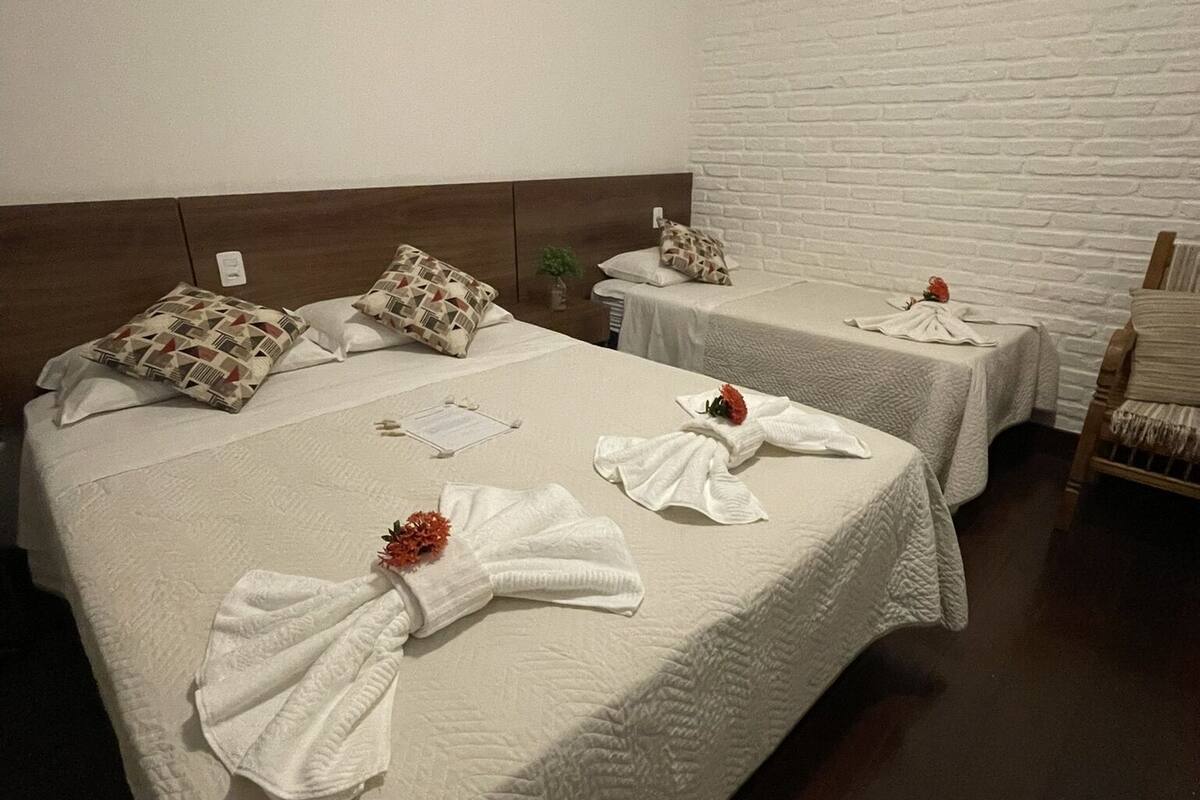 A hotel room with two beds, each with a white quilted bedspread and decorative towels.