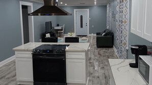 A modern kitchen with a central island, built-in oven, and stainless steel range hood. - Countryside to Citywide
Workers Paradise 
MTR
Great price
No Cleaning Fee (Slidell)