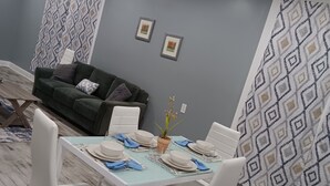 A dining area with a table set for four, white chairs, and a green sofa in the background. - Countryside to Citywide
Workers Paradise 
MTR
Great price
No Cleaning Fee (Slidell)