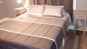 A neatly made bed with a brown and gray bedspread, a bedside table with a lamp, and a small nightstand. - Countryside to Citywide
Workers Paradise 
MTR
Great price
No Cleaning Fee (Slidell)
