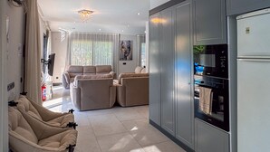 Una sala moderna con un conjunto de sofás, un comedor con refrigerador y microondas, y una cocina con armarios.