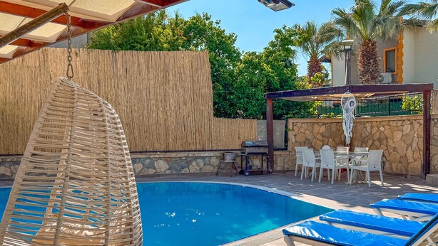 Una piscina con sillas de descanso y una pérgola.