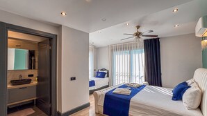 Una habitación de hotel moderna con una cama grande, un lavamanos integrado y un ventilador de techo.