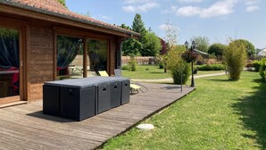 Une terrasse en bois dotée d’un jacuzzi intégré et d’un espace salon abrité.