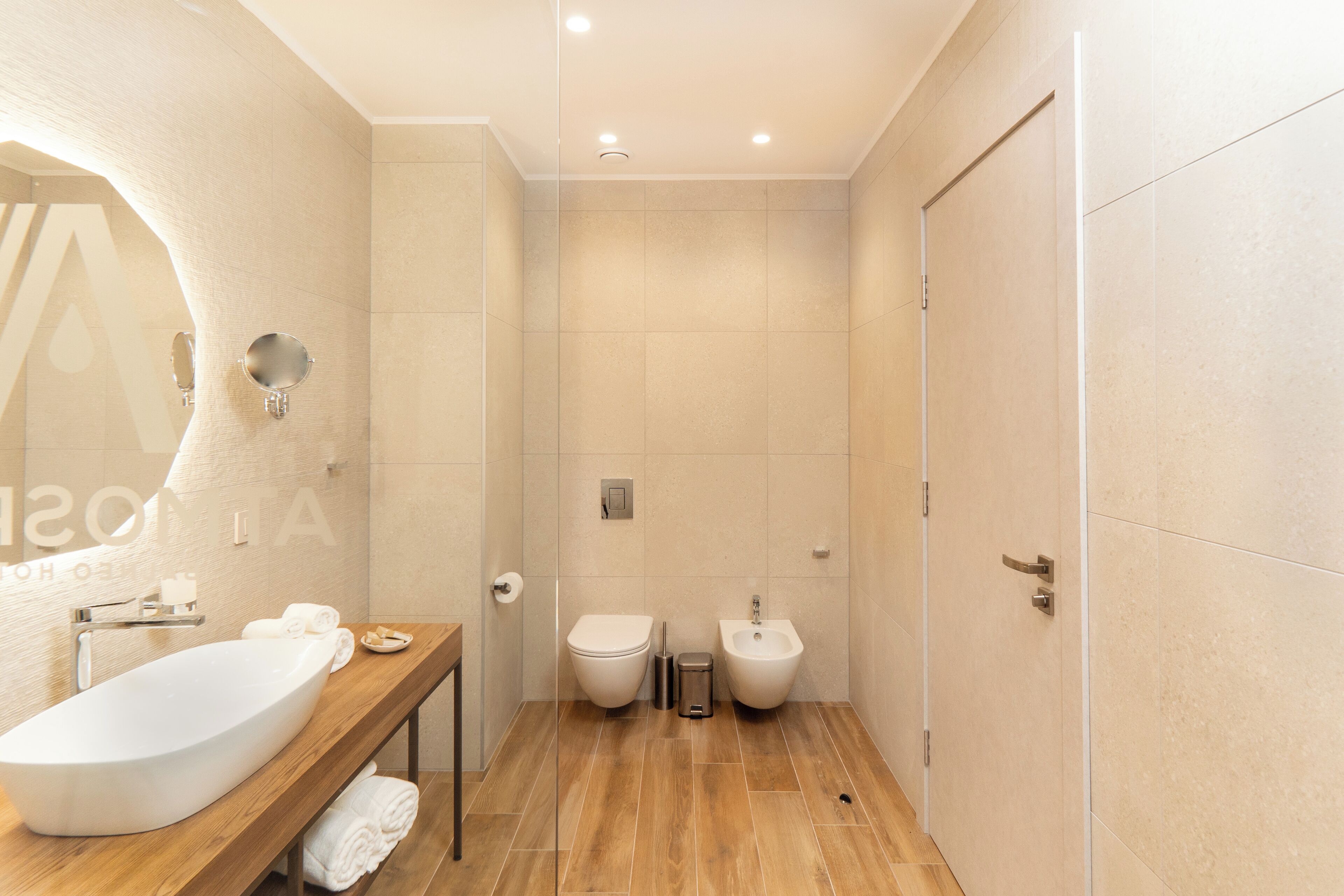 Une salle de bain moderne avec un meuble-lavabo en bois, un grand lavabo, un bidet et des toilettes.