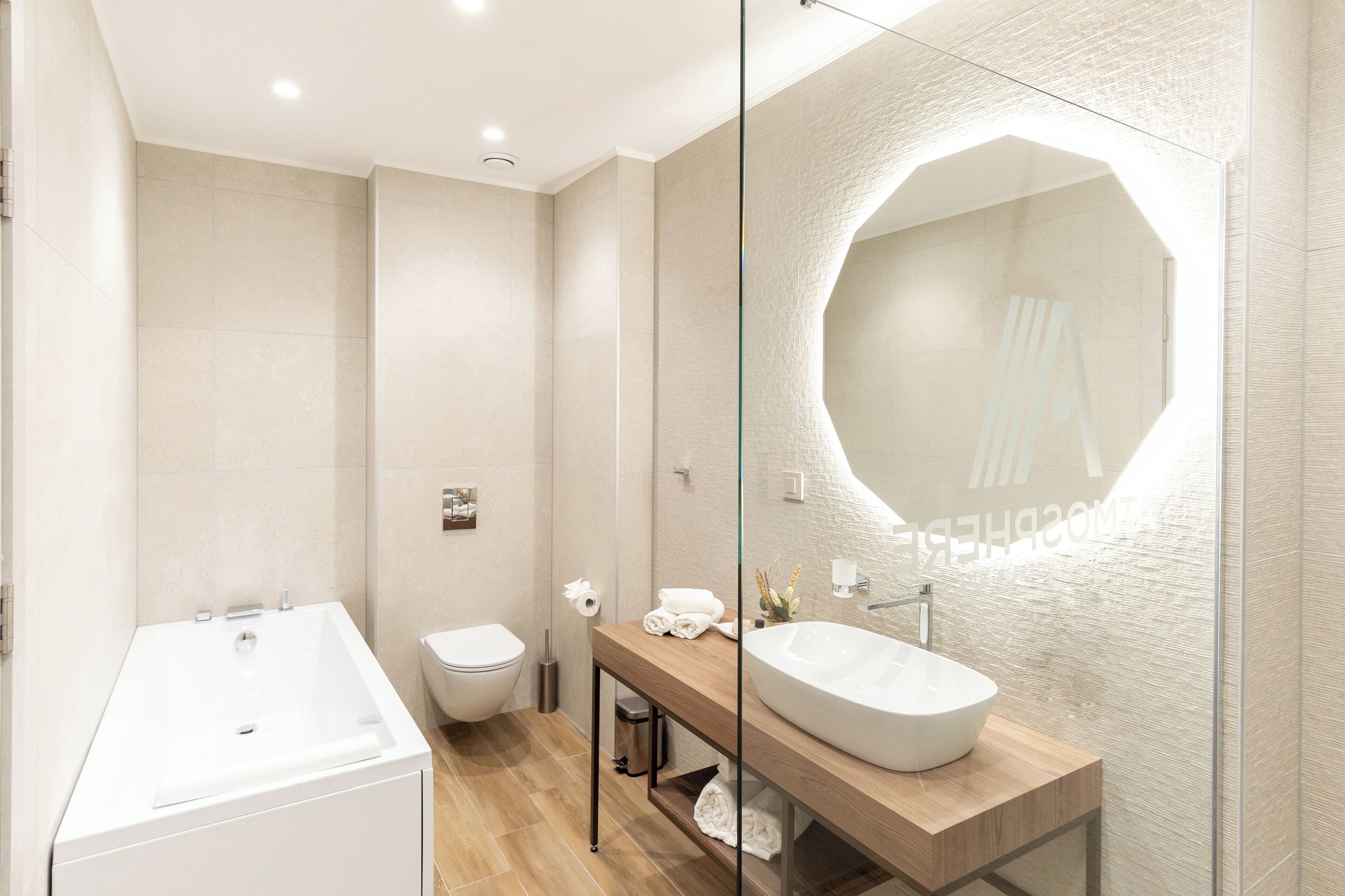 Un baño moderno con una bañera independiente, un inodoro y un tocador con un espejo grande.