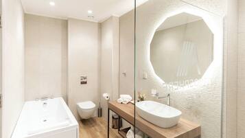 Un baño moderno con una bañera independiente, un inodoro y un tocador con un espejo grande.