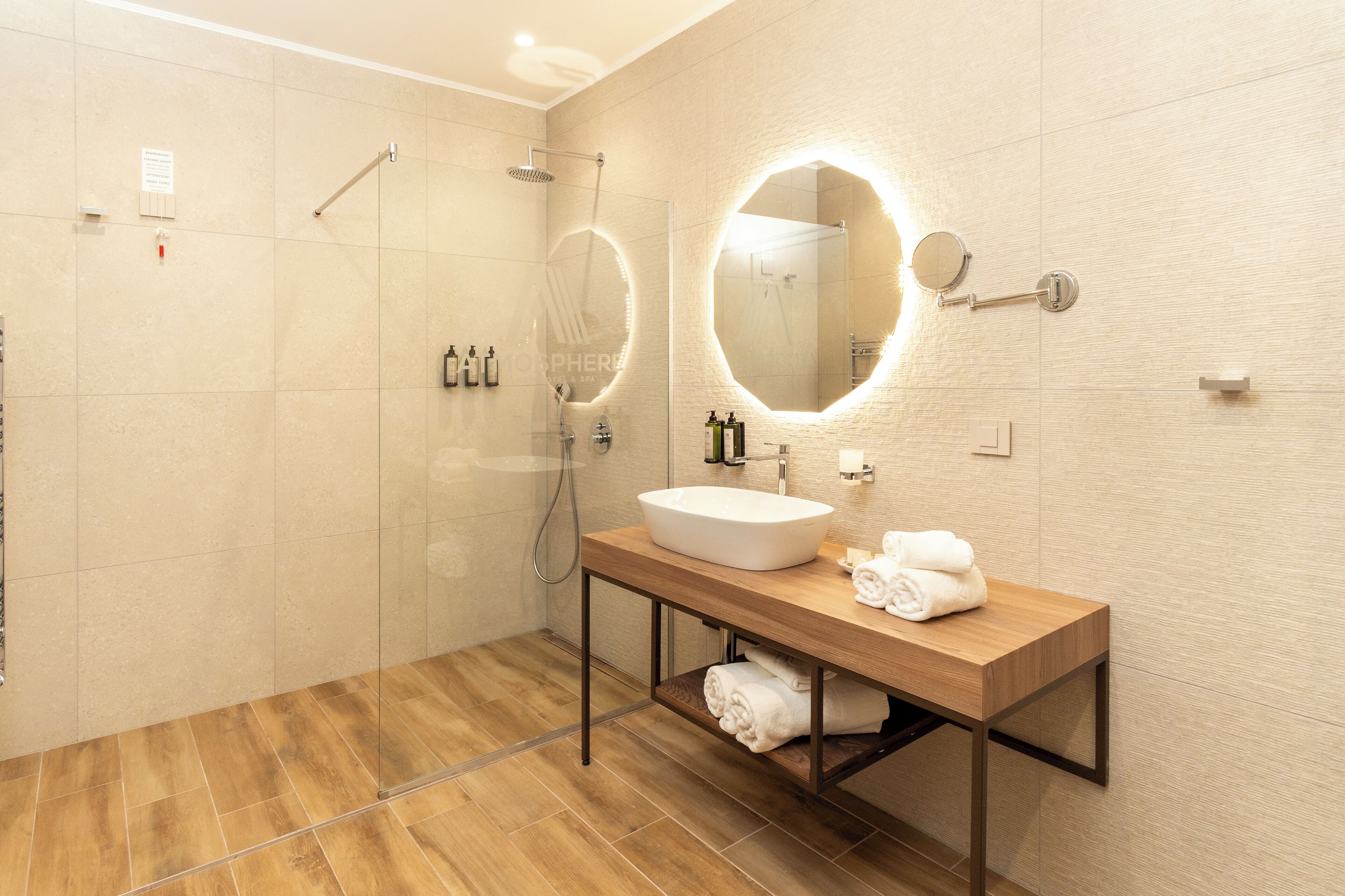 A modern bathroom with a wooden vanity, a large mirror, and a glass-enclosed shower.