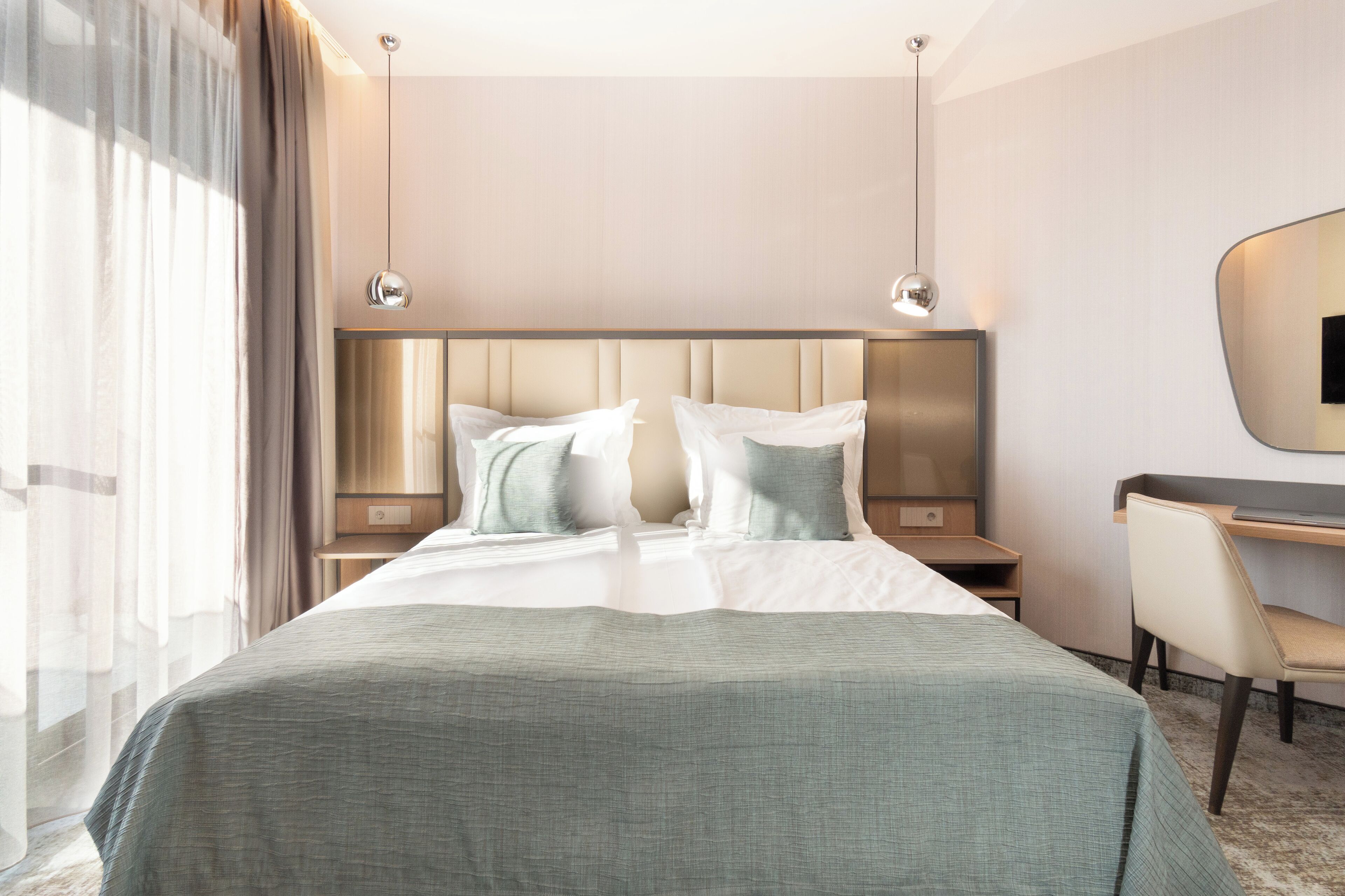 Une chambre d’hôtel avec un grand lit, deux tables de chevet, un bureau et une chaise.