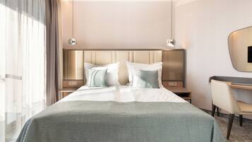 Une chambre d’hôtel avec un grand lit, deux tables de chevet, un bureau et une chaise.