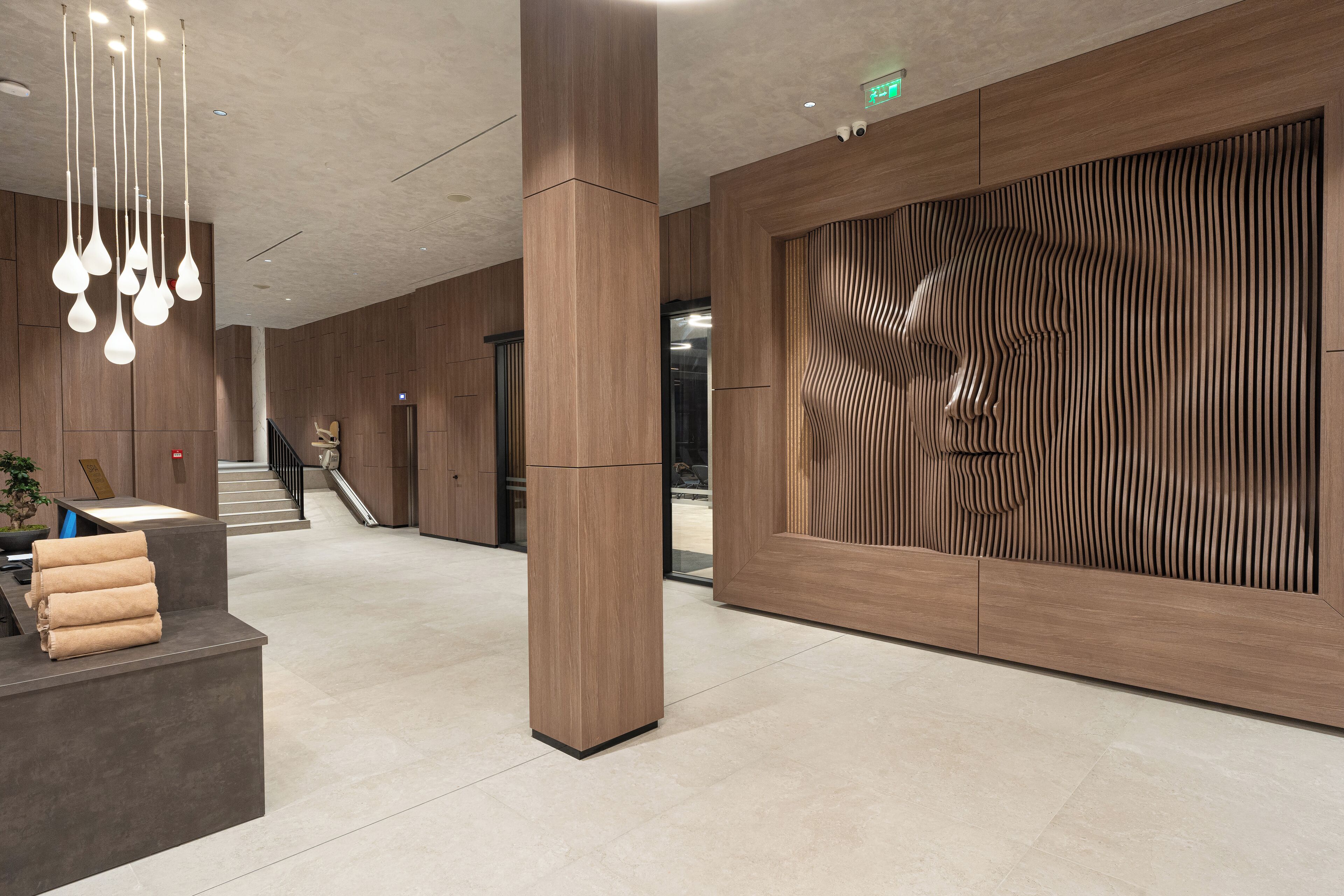 Un vestíbulo moderno con mostrador de recepción, una escalera y un diseño único en madera.