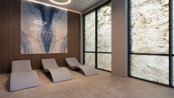 Relax in a serene spa room with lounge chairs and a stunning wall feature.