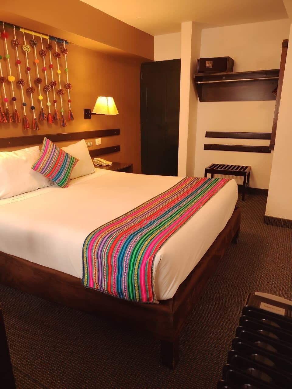Une chambre d’hôtel avec un grand lit, une lampe de chevet, un téléviseur fixé au mur et une petite table.
