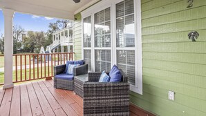 A covered porch with wicker furniture and a ceiling fan. - The Wave @ Coastal Retreat Villas (Long Beach)