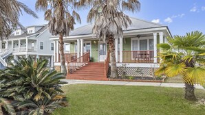 A two-story house with a porch, red railings, and a well-maintained lawn. - The Wave @ Coastal Retreat Villas (Long Beach)