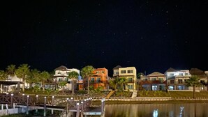 Una propiedad frente al agua con varios edificios, un muelle y una masa de agua tranquila que refleja las estructuras.