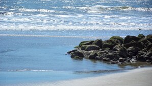Una playa con olas rompiendo sobre rocas y arena.