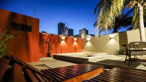 Una terraza en la azotea con piscina, zona de estar y plantas en macetas.