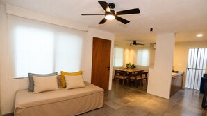 Una sala de estar con sofá, mesa de comedor y zona de cocina.