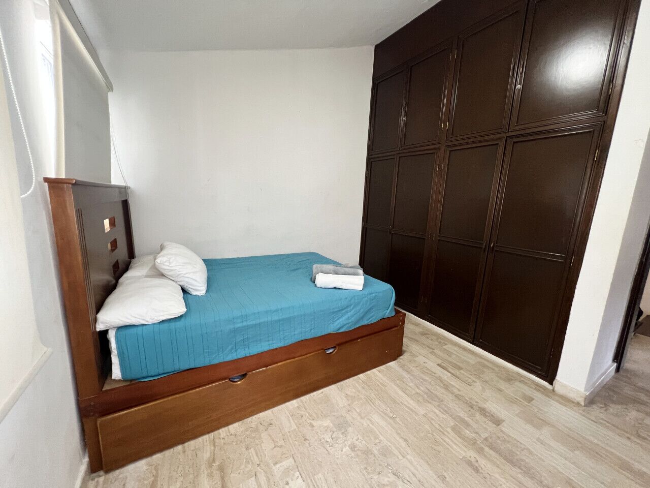 A bedroom with a bed, a wardrobe, and a wooden floor.