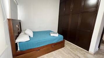 A bedroom with a bed, a wardrobe, and a wooden floor.