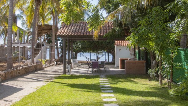 A covered outdoor seating area with a view of the sea, surrounded by palm trees and greenery. - Altata, casa Las Aguilas (Altata)