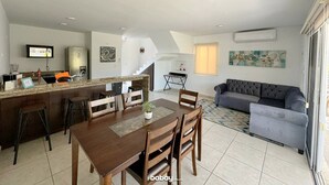 A modern living space with a kitchen, dining area, and a gray sofa. - Casa en nuevo Altata, Punta Esmeralda Grand (Nuevo Altata)