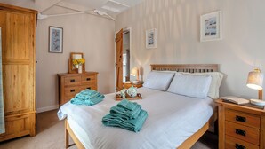 Ein ordentlich eingerichtetes Schlafzimmer mit einem großen Bett, Holzmöbeln und einem Deckenventilator.